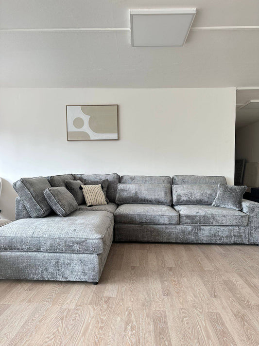 Canapé d'angle Lexus Marbella beige de la marque HomeDeLuxe, avec coussins confortables et revêtement en tissu dans un salon moderne.