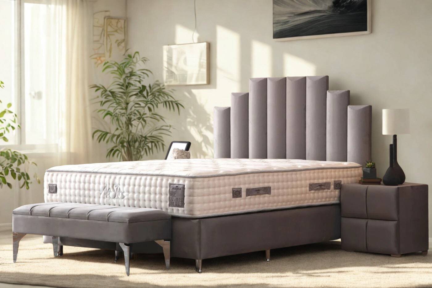 Lit coffre HomeDeLuxe NATURA en velours gris, avec tête de lit rembourrée et espace de rangement intégré, dans une chambre élégante.