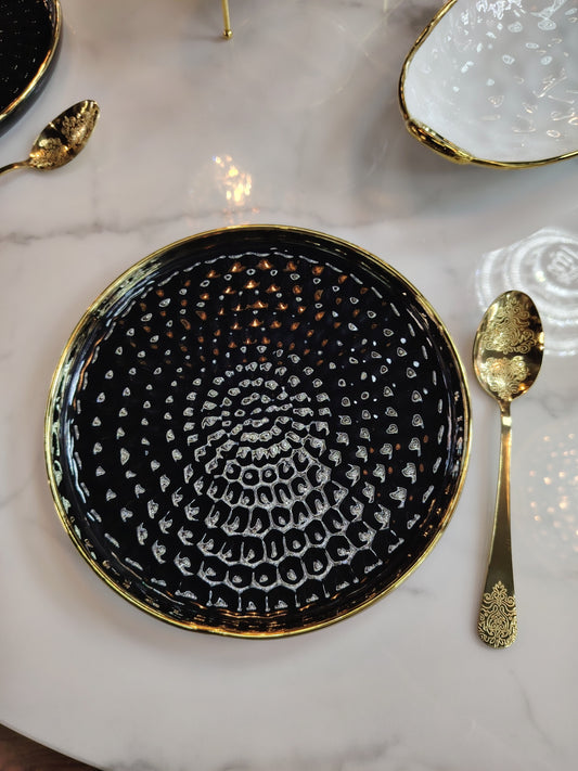 Assiettes noires et dorées du service de table HomeDeLuxe, design élégant avec finition brillante, vue en gros plan.