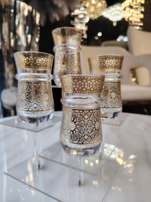 12 petits verres à thé en verre transparent, de la marque HomeDeLuxe, disposés sur une surface blanche.