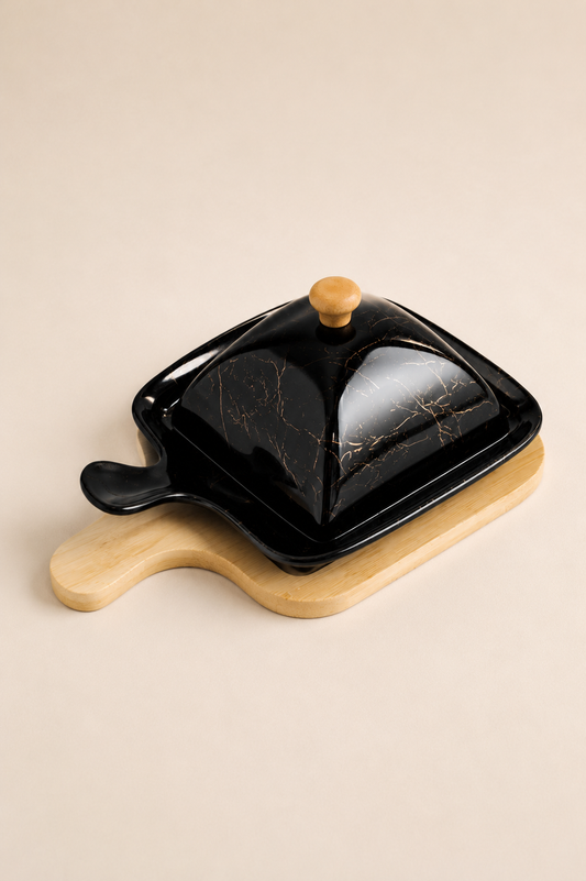 Beurrier en céramique blanc de la marque HomeDeLuxe, avec couvercle en bois, placé sur une table en bois.