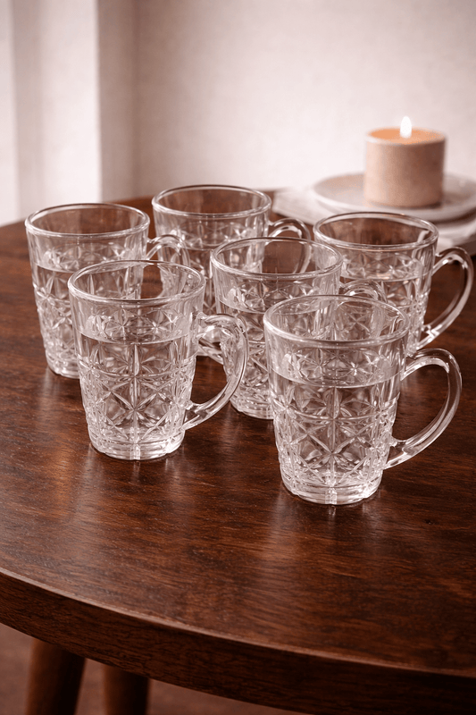 Six verres à café en verre transparent de la marque HomeDeLuxe, empilés sur une surface lumineuse.