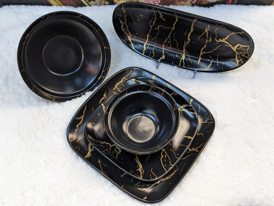 Service de table noir en marbre de la marque HomeDeLuxe, ensemble élégant avec assiettes et couverts visibles.