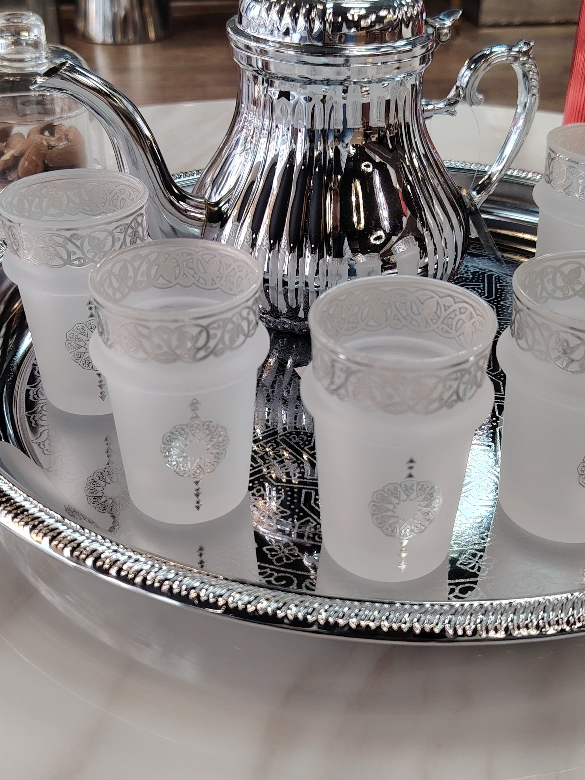 Douze verres à thé en argent massif de la marque HomeDeLuxe, élégants et raffinés, disposés sur une table en bois.