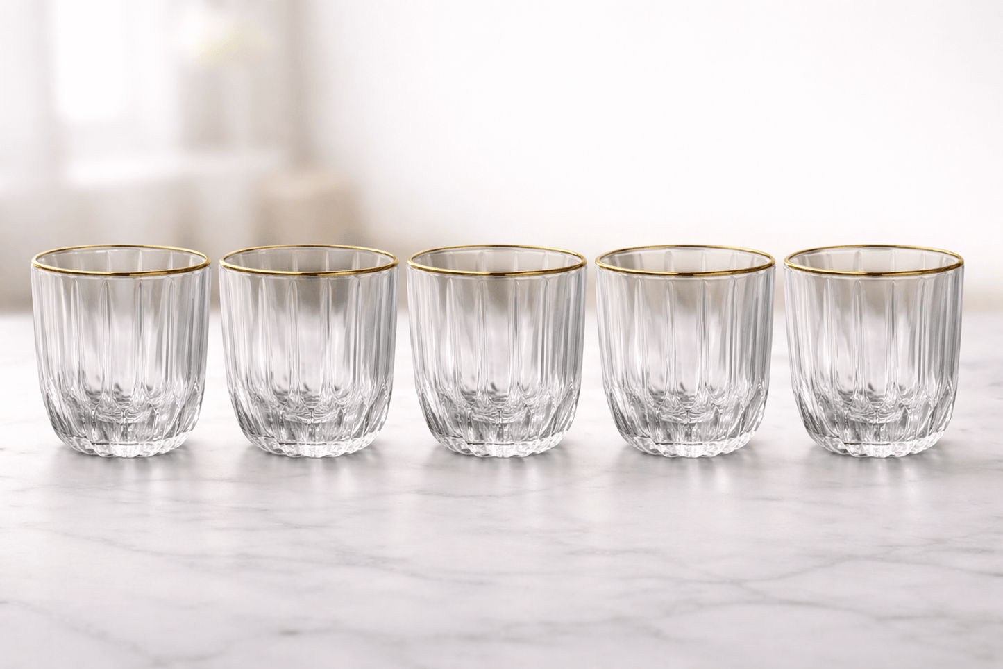 Six verres en verre avec finition or de la marque HomeDeLuxe, élégants et transparents, posés sur une surface claire.