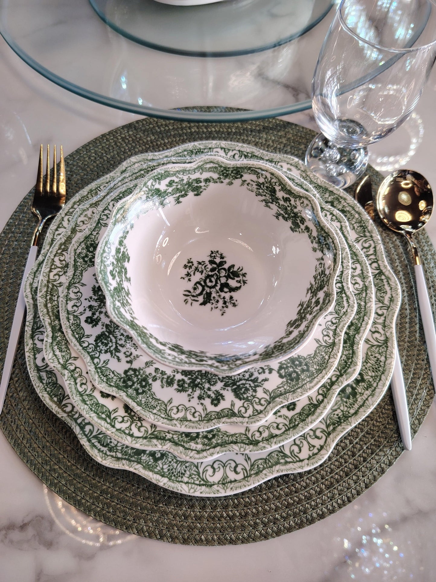 Service de table vert HomeDeLuxe avec assiettes, verres et couverts élégants pour repas sophistiqués.