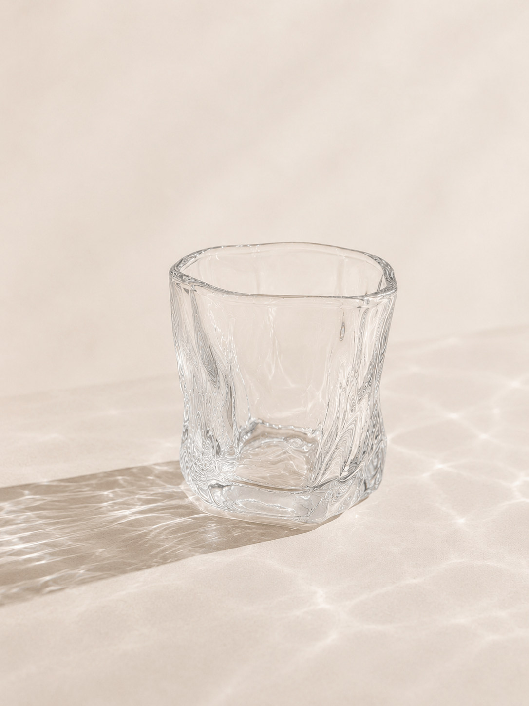 Douze petits verres à eau en verre transparent de la marque HomeDeLuxe, alignés sur une surface blanche.