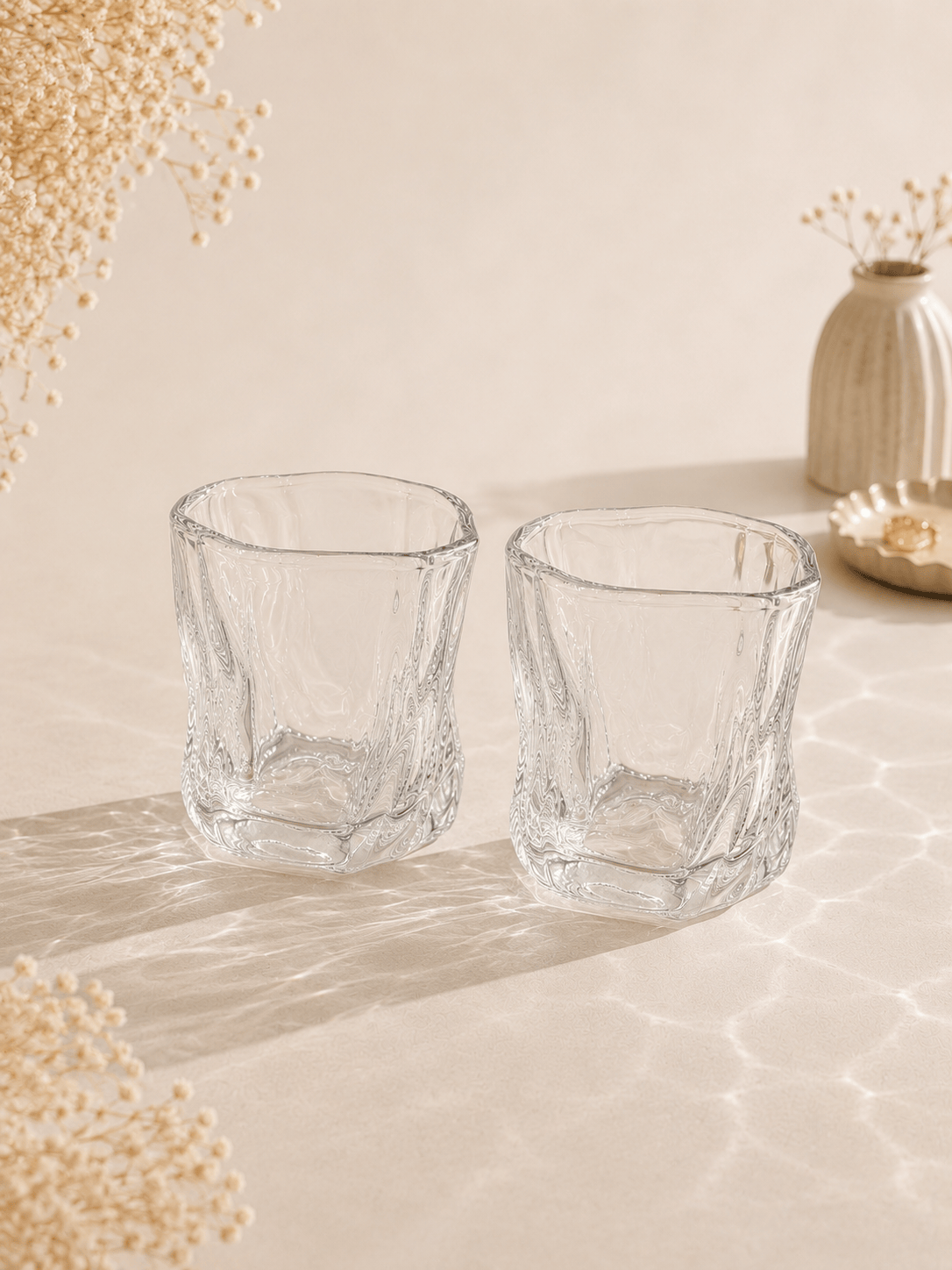 Douze petits verres à eau en verre transparent de la marque HomeDeLuxe, disposés sur une table.