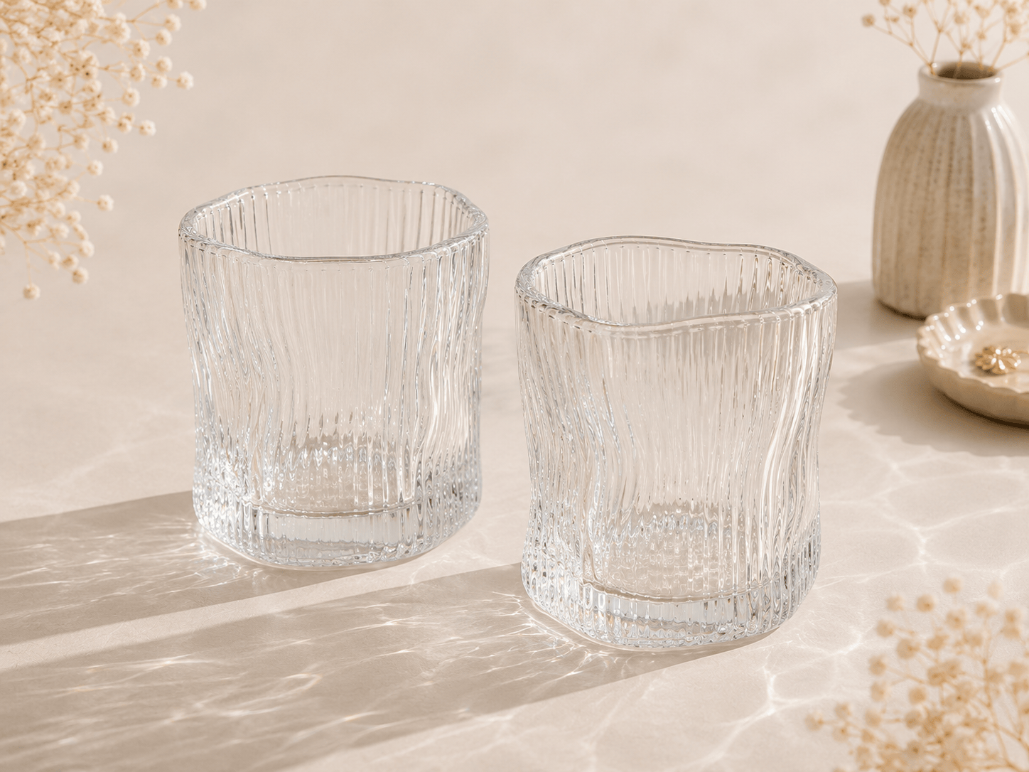 Douze petits verres à eau en verre transparent de la marque HomeDeLuxe, alignés sur une surface.